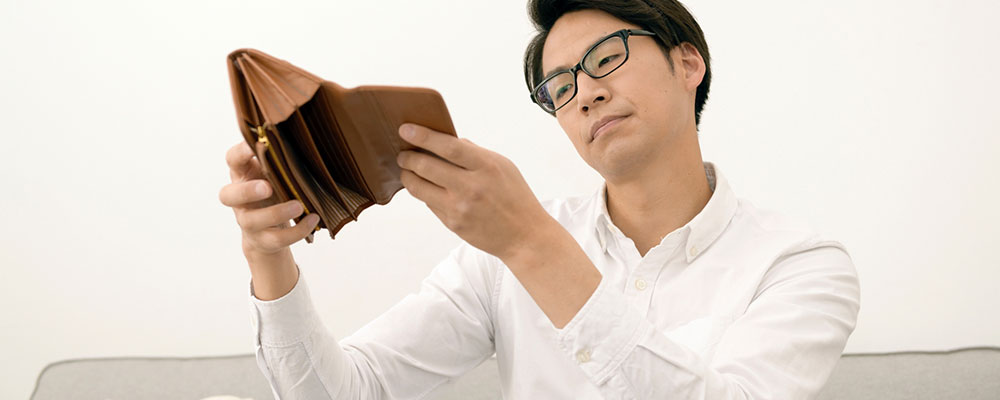 金欠でお金が入っていない財布を見つめる男性